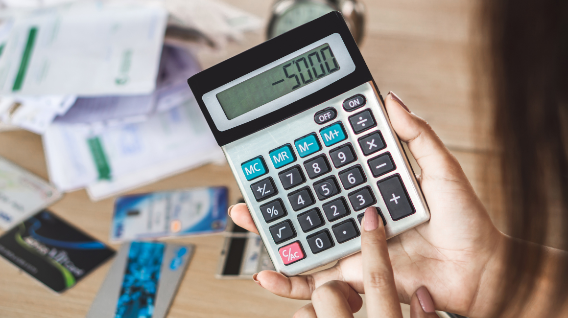 Kobieta trzymająca kalkulator z wynikiem -5000, na tle rachunków i kart płatniczych