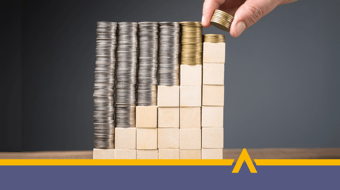 Stosy monet ułożone na drewnianych klockach tworzących rosnący wykres, symbolizujący wzrost finansów i oszczędności.